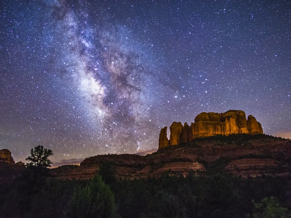 milky way over a rock formation on a mountain