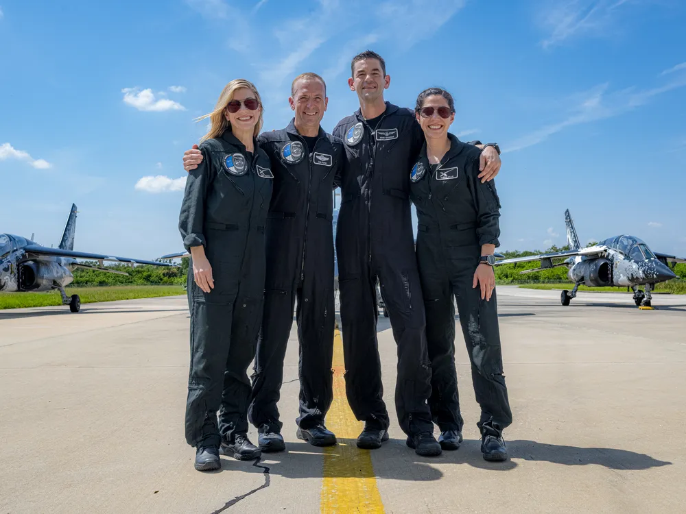 Four people in blue suits stand on a runway