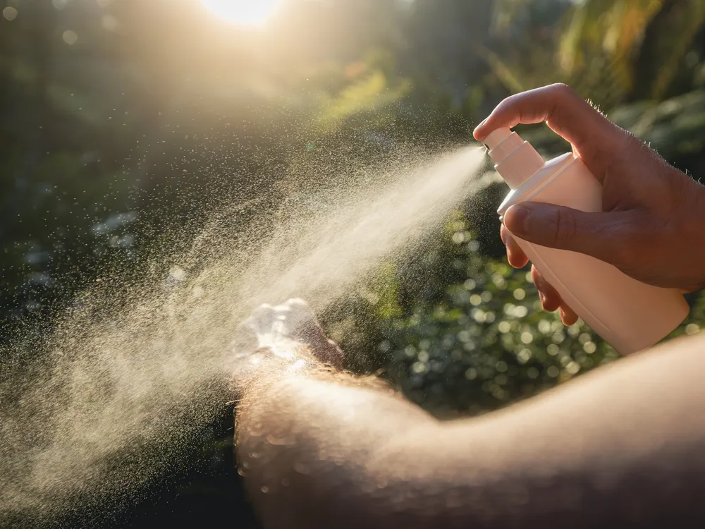 A person spraying their am with bug spray