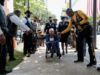 a woman veteran rolling in her wheel chair receives a standing ovation from military veterans