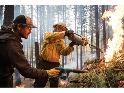 Opener - Saylor Flett, left, fans flames ignited by Jeff Greef. Air quality, weather and even bird migration affect when it’s safe to conduct a burn.