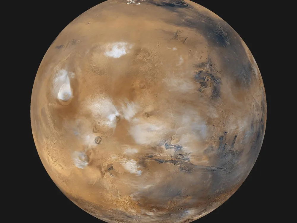 The entire planet Mars seen from space with bluish-white water ice clouds above volcanoes